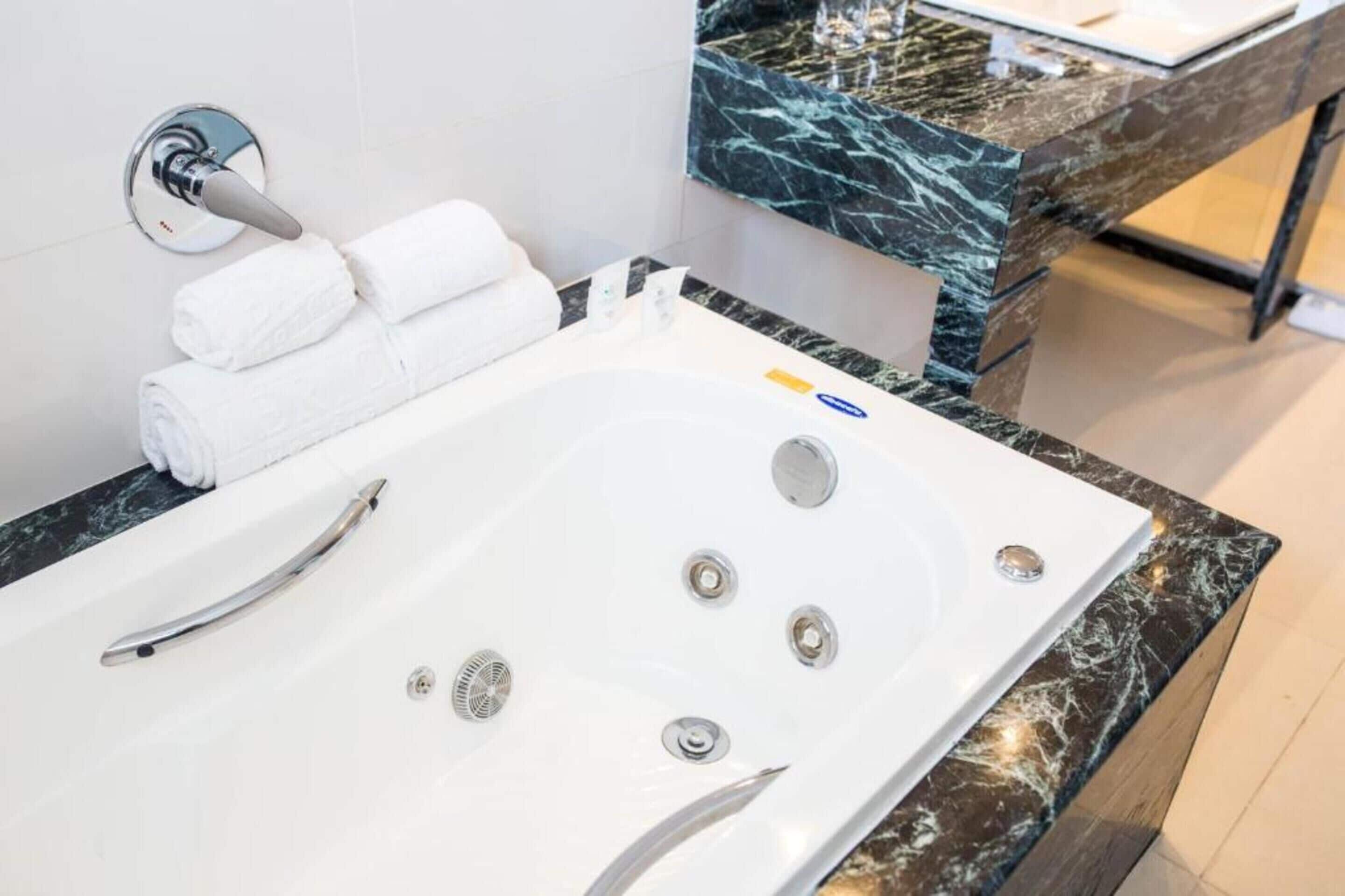 Une salle de bain moderne avec une grande baignoire blanche, un robinet chromé et un comptoir en marbre.