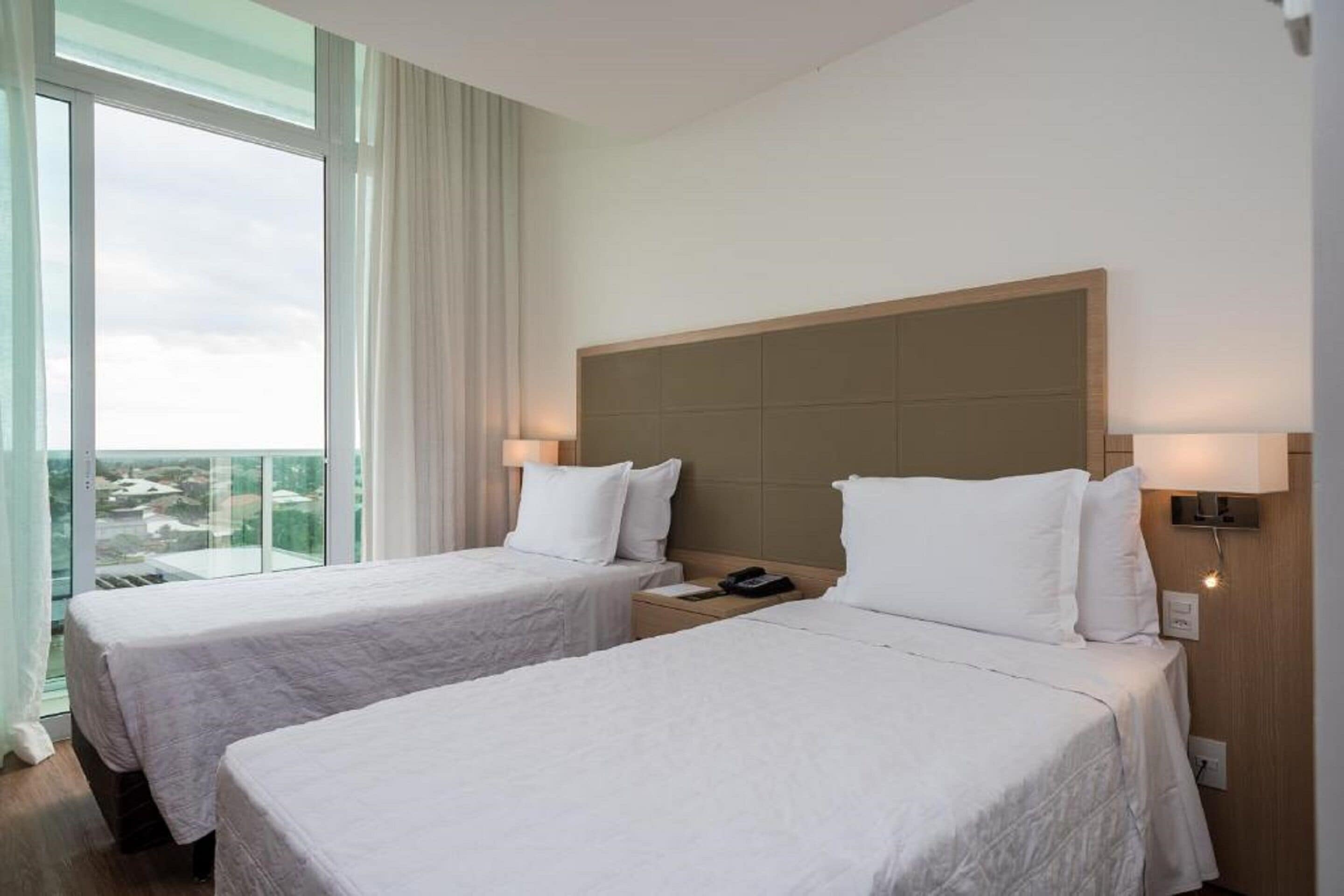 Une chambre d’hôtel avec deux lits, une grande fenêtre et une vue sur la ville.