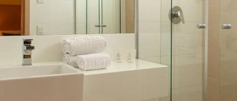 A modern bathroom with a glass-enclosed shower, a white sink with a mirror above it, and a toilet.