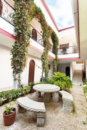 Un patio con un banco de piedra, plantas en macetas y una escalera.
