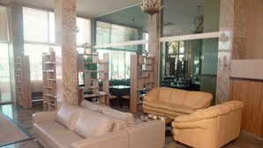 Een ruime woonkamer met een beige bank, een salontafel en inbouwplanken.