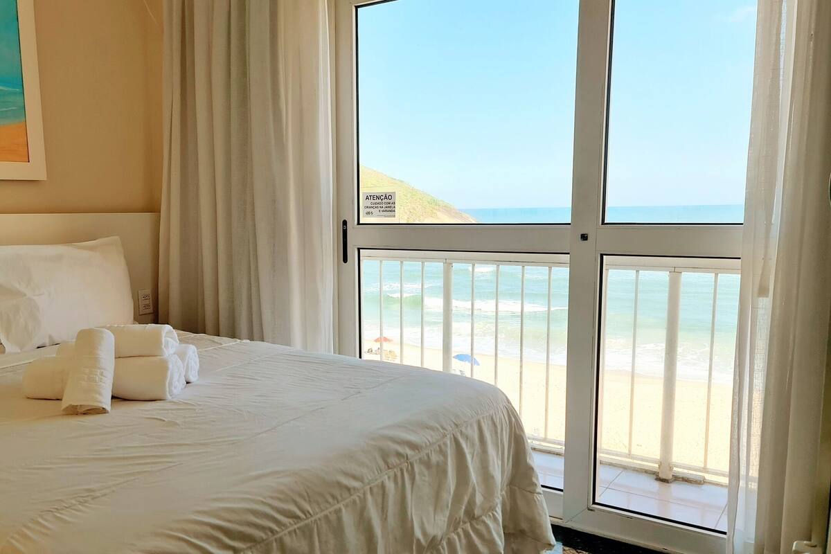 Un cuarto de hotel con un ventanal que ofrece vistas a la playa y al océano.