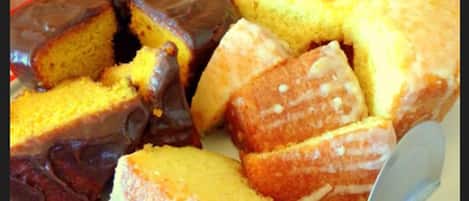 A cake with a chocolate glaze and a yellow sponge, cut into pieces on a plate.