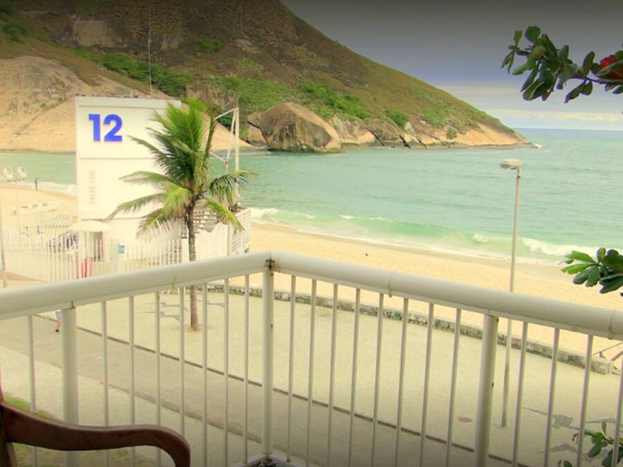 Un balcone con vista su una spiaggia, una palma e un cartello con il numero 12.