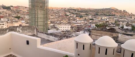 A rooftop terrace with a view of a densely packed cityscape, including a building under construction.