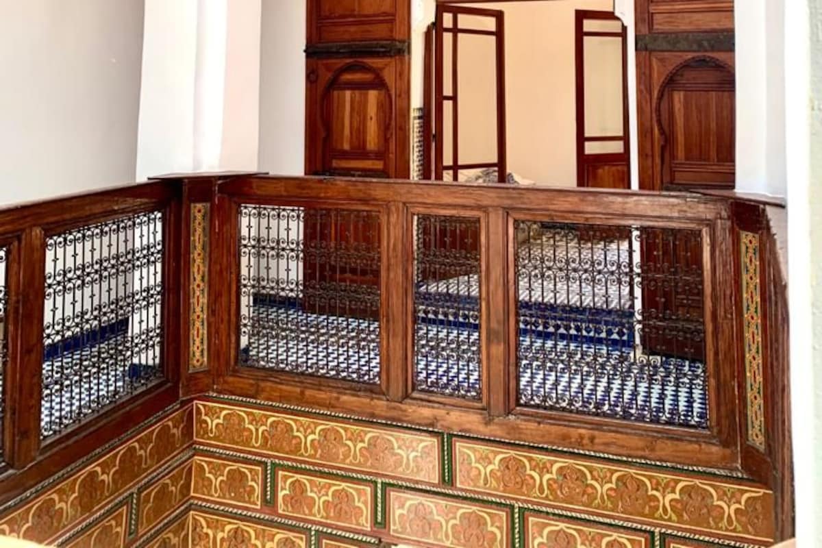 Un intérieur traditionnel, agrémenté d’arcs décoratifs, de portes en bois et de motifs complexes dans les carreaux.