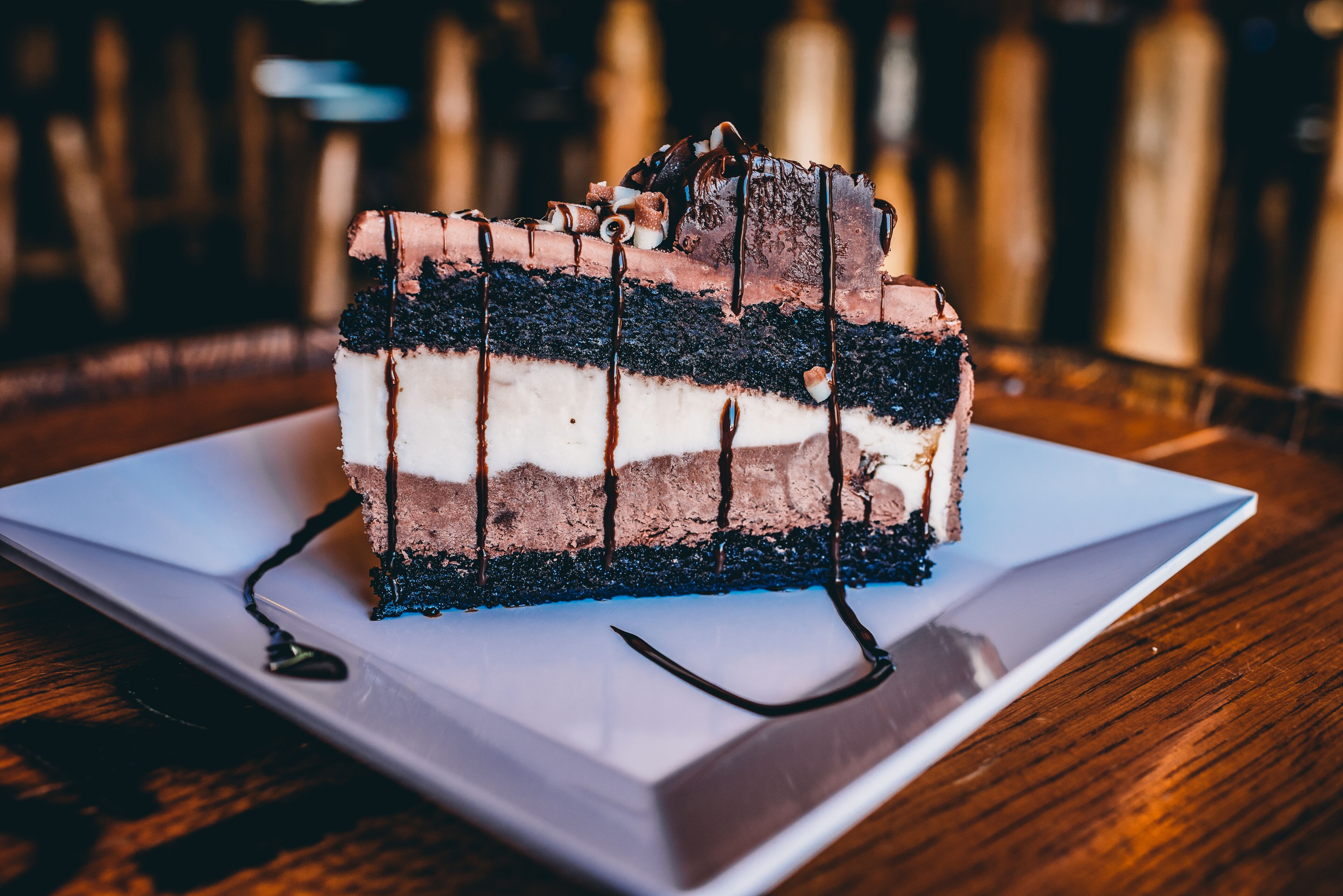 A slice of layered cake with chocolate and white frosting on a white plate.