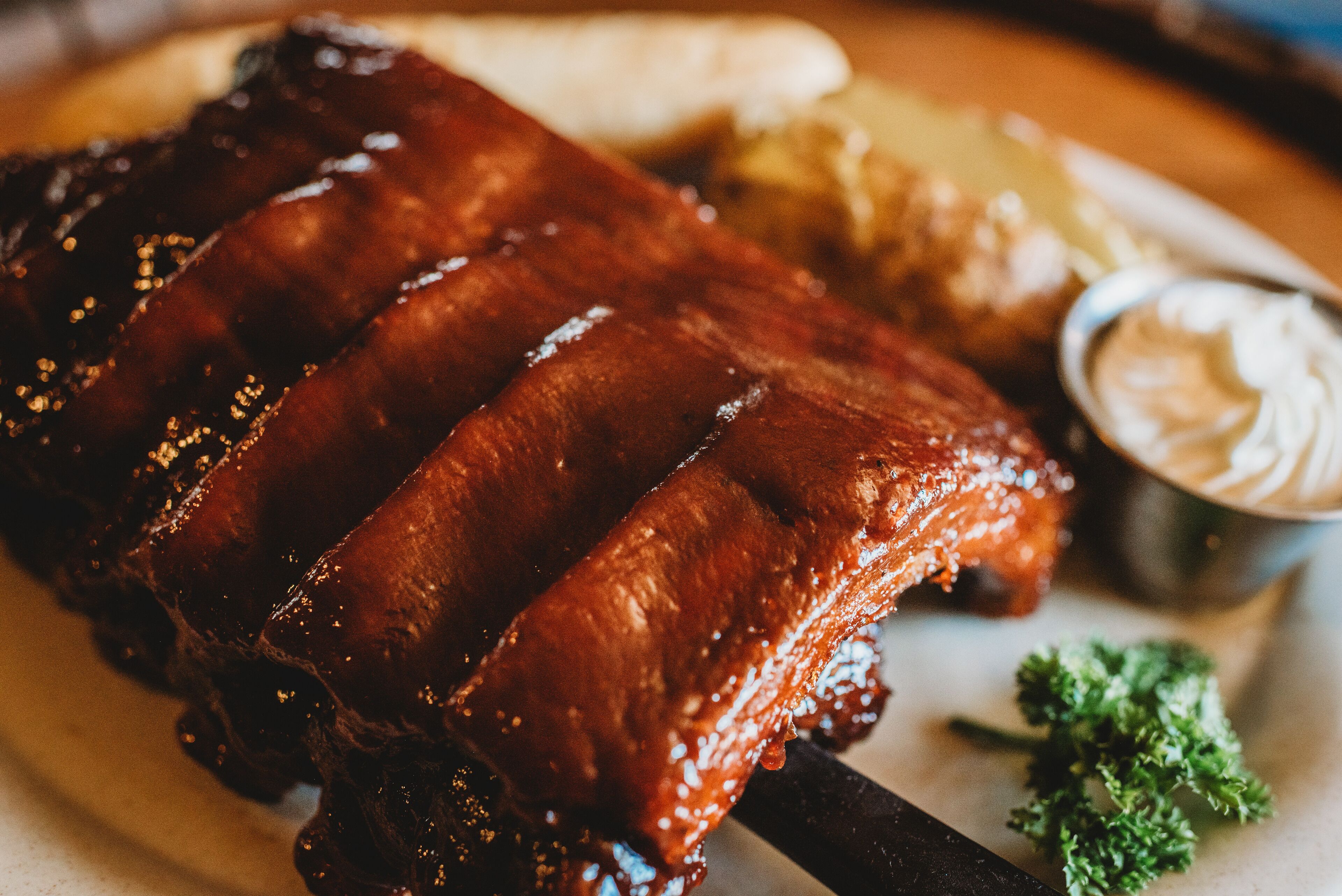 Ein Teller mit gegrillten Rippchen, dazu Krautsalat und eine kleine Schüssel Sauce.