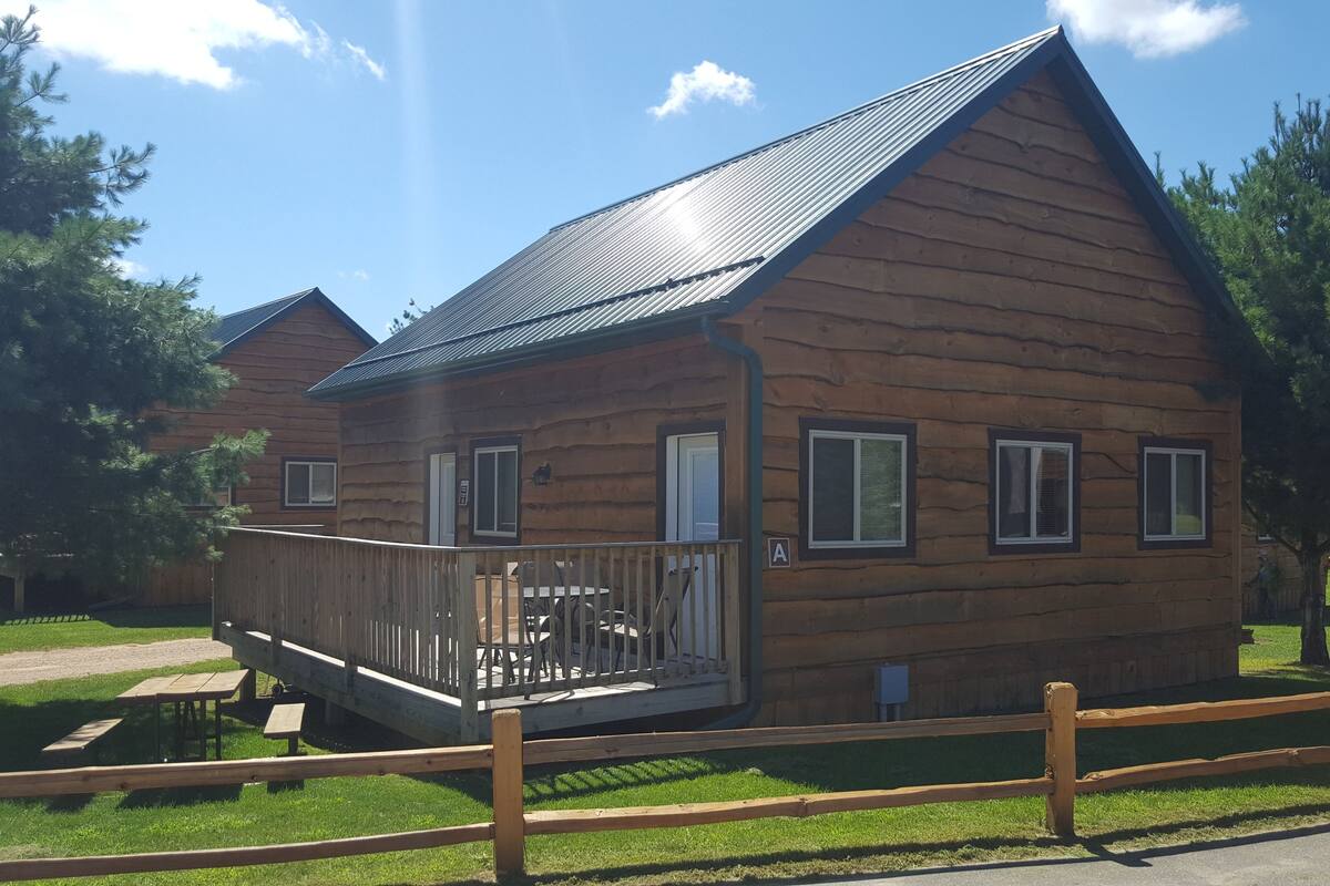 A log cabin with a balcony, a picnic table, and a fenced yard.