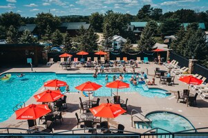 A pool area with multiple red umbrellas, lounge chairs, and a hot tub.