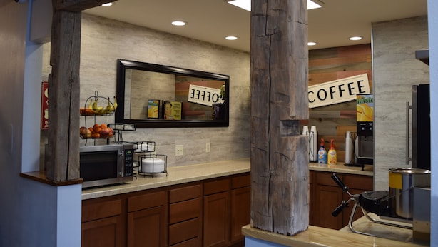A kitchen with wooden cabinets, a microwave, a coffee machine, and a sign that says "COFFEE". - Mountain View Hotel (Killdeer)