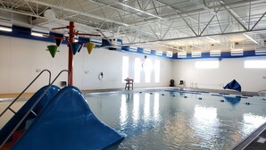 An indoor swimming pool with a blue slide, a lifeguard chair, and a sunshade. - Mountain View Hotel (Killdeer)