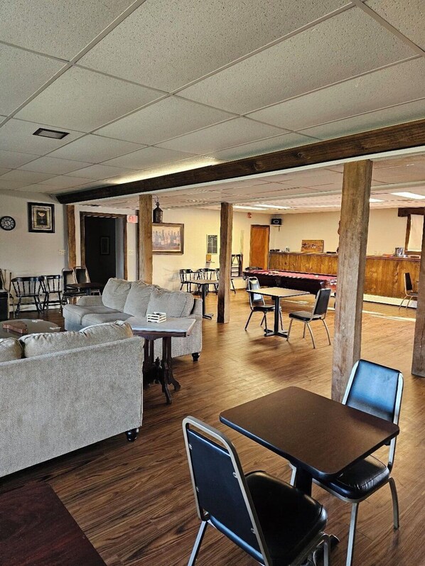 A spacious room with a pool table, a sofa, and several chairs. - Lake Shore Farm Inn (Northwood)