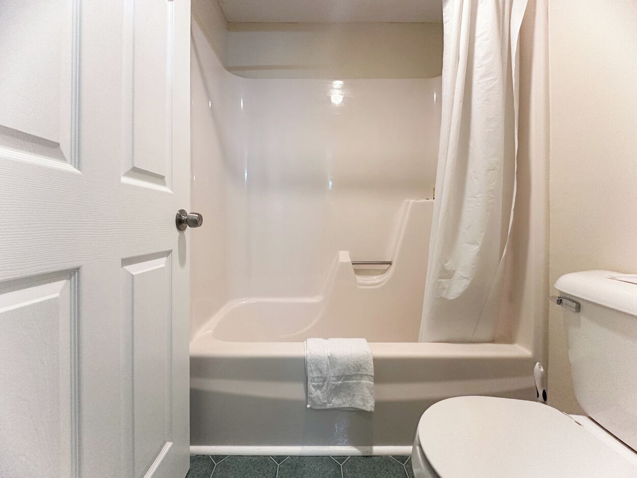 A bathroom with a bathtub, toilet, and shower curtain.