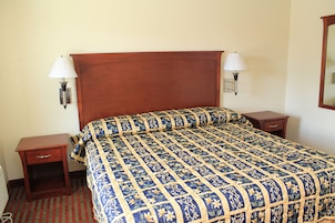 Una habitación de hotel con una cama grande, dos mesitas de noche y dos lámparas de pared.