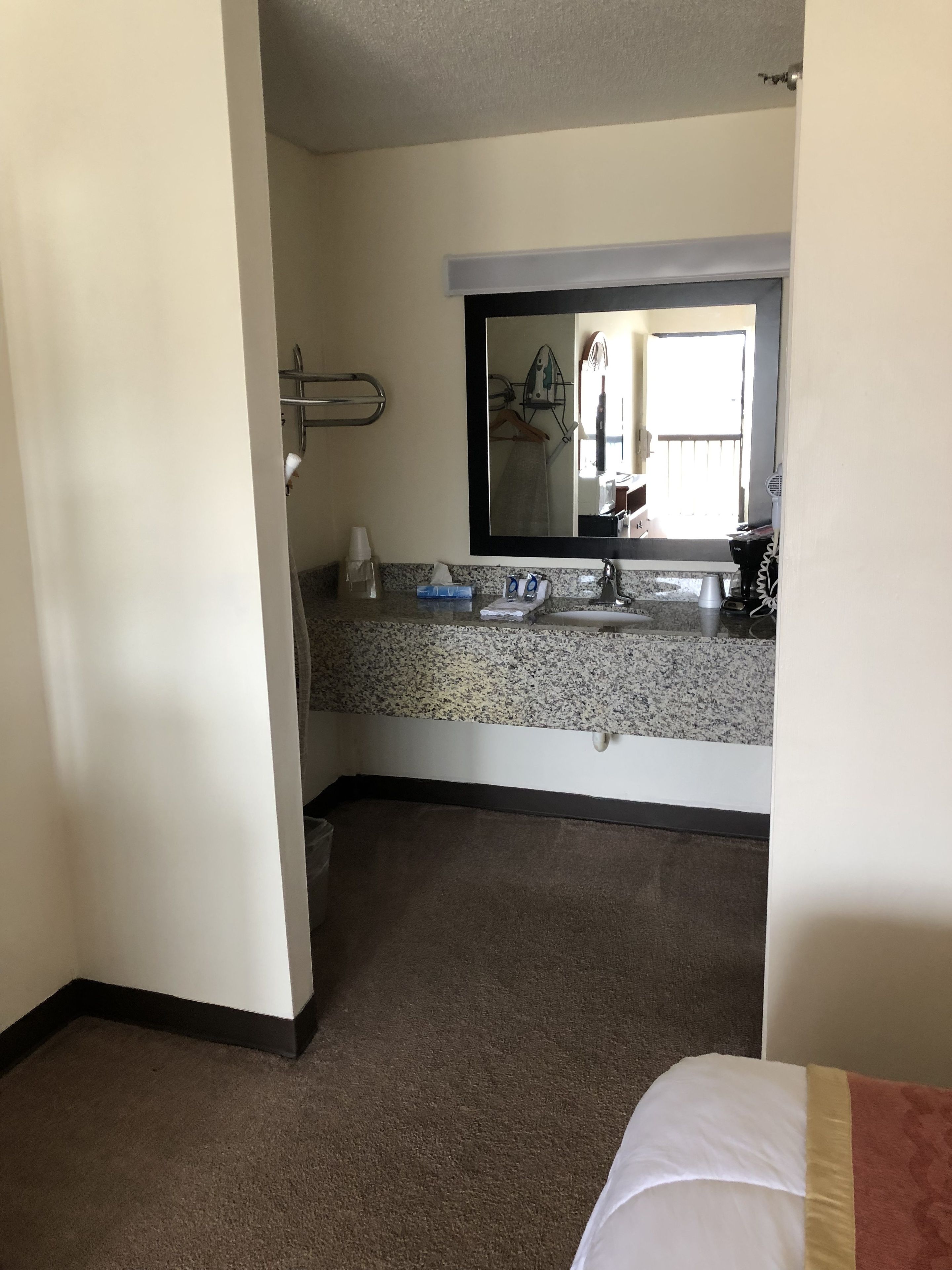 A hotel bathroom with a granite countertop, sink, and mirror.