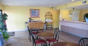A restaurant with a counter, chairs, a microwave, and a painting on the wall.