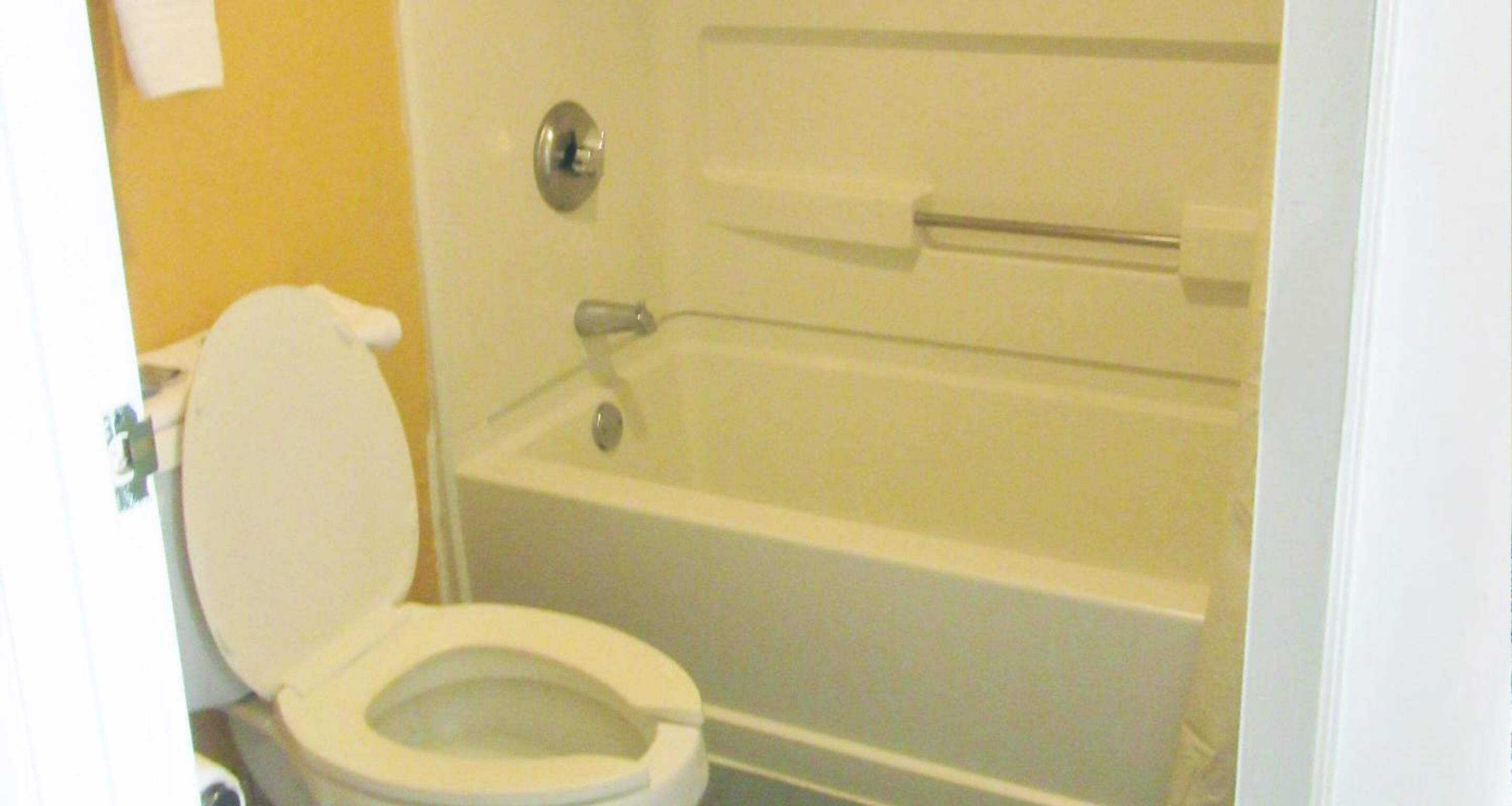 Een standaard badkamer met toilet, bad en douche.