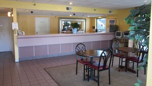 A restaurant interior with a counter, chairs, a table, and a potted plant. - Travel Inn (Lugoff)