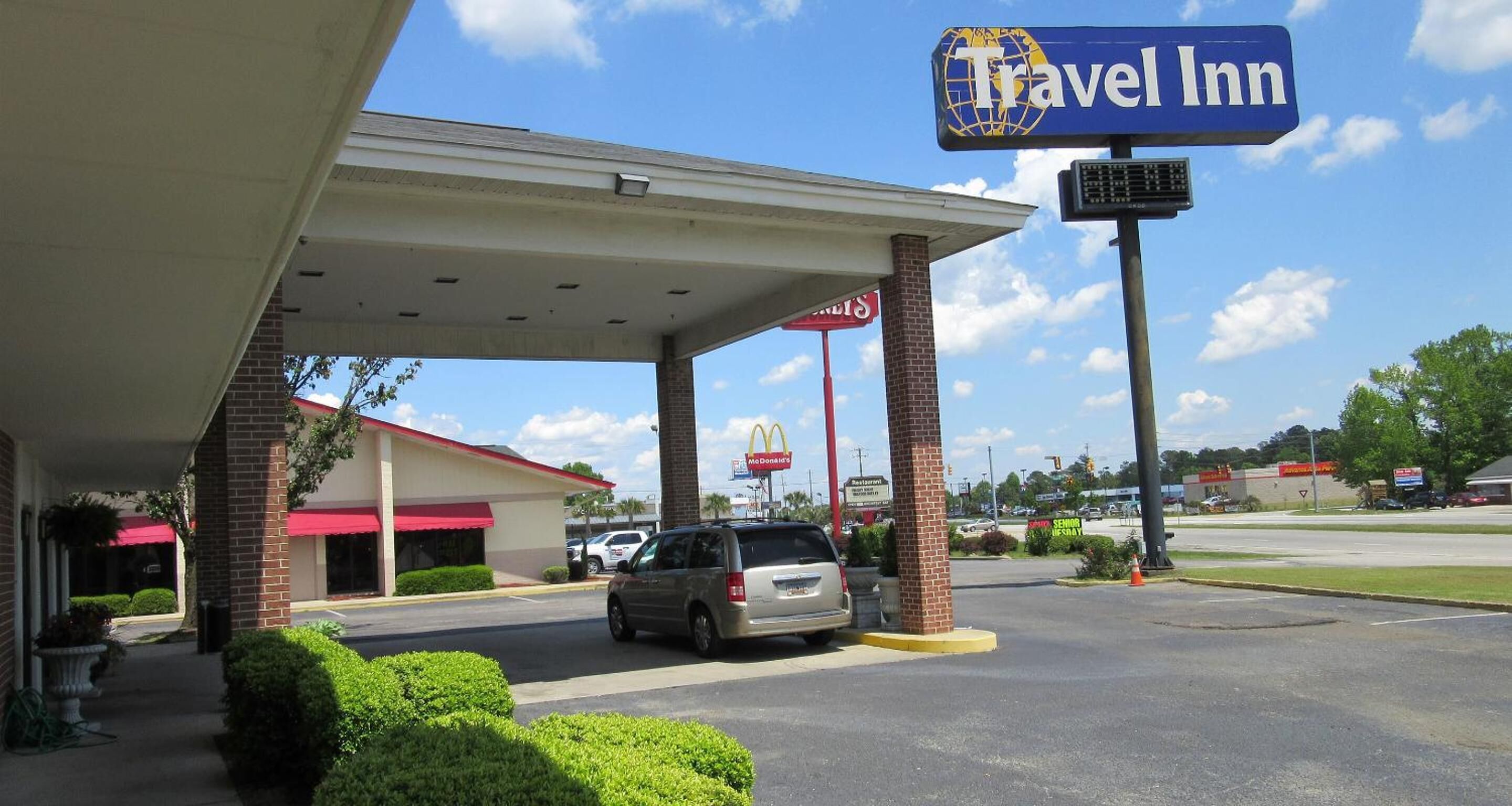 Un hôtel de chaîne proposant un parking couvert, un restaurant McDonald's et un panneau indiquant la présence d'un service d'assistance aux personnes âgées.