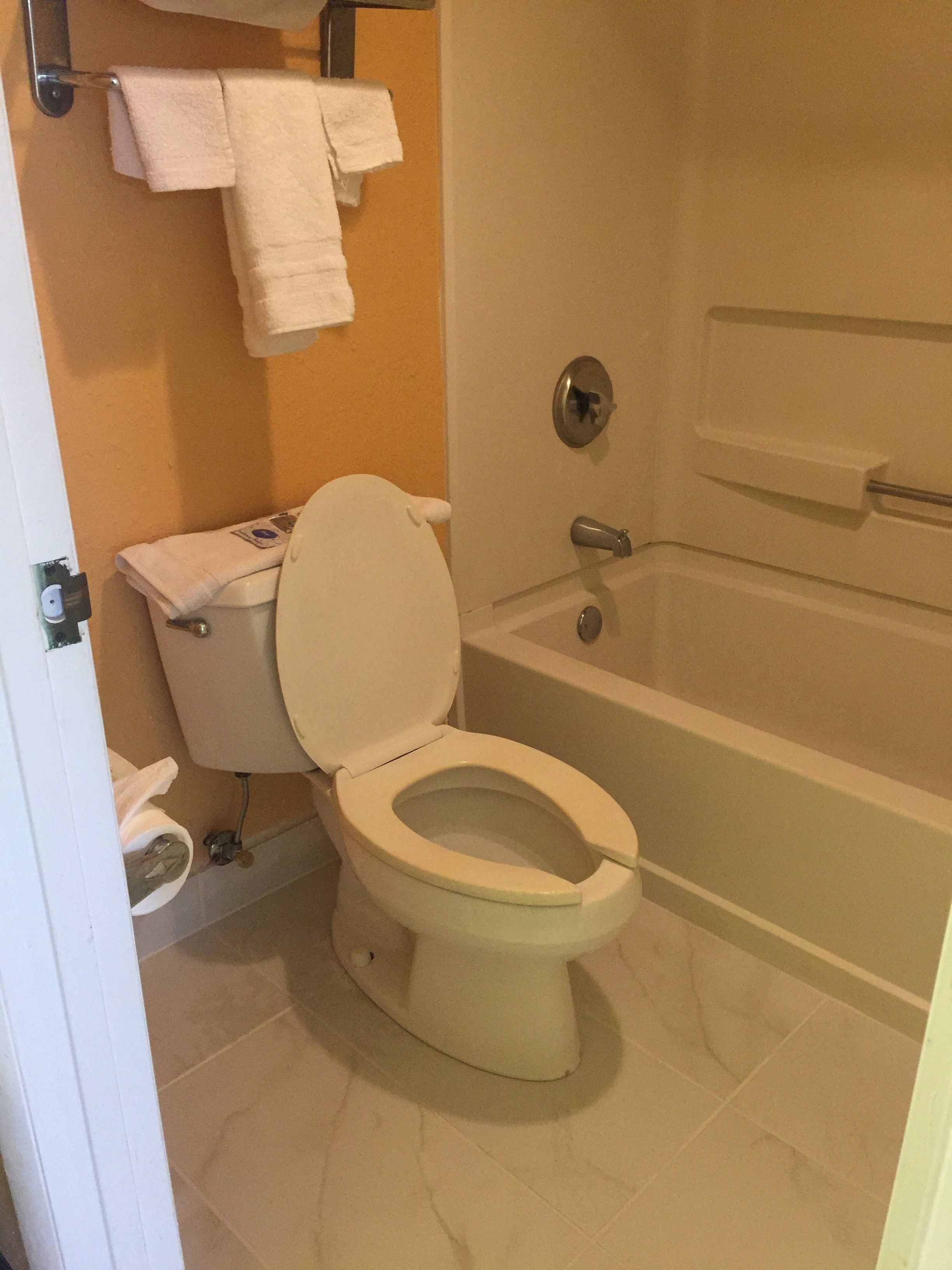 Un baño con inodoro, bañera y toallero con toallas.