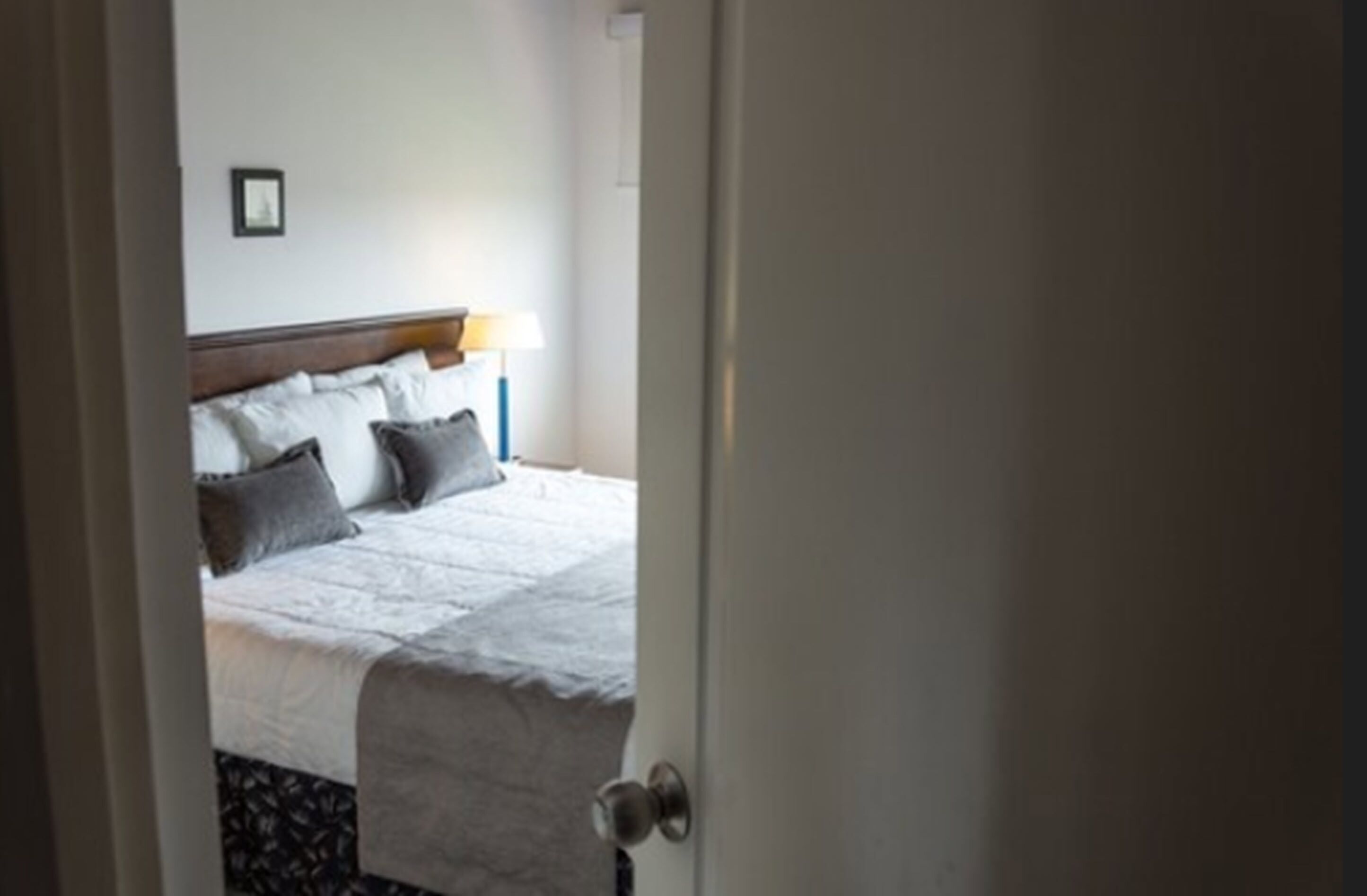 Una camera d'albergo con un letto, un comodino e una lampada.
