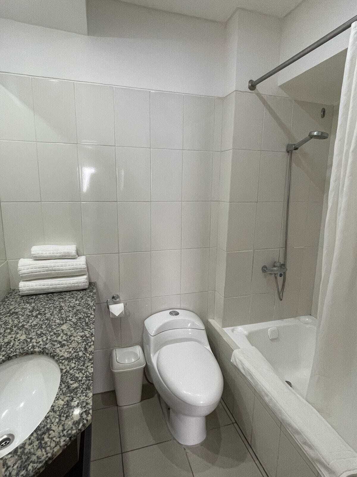 Et badeværelse med toilet, håndvask og brusebad.
