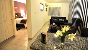 Una habitación de hotel con una cama, un sofá, una mesita de centro y un jarrón con flores.