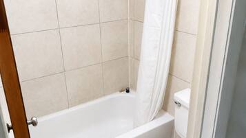 A bathroom with a bathtub, toilet, and shower curtain.