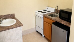 A compact kitchen with a sink, stove, microwave, and refrigerator.