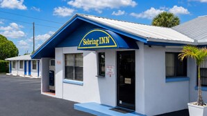 A motel named 'Sebring Inn' with a blue and white exterior, a visible parking lot, and a palm tree in the foreground.