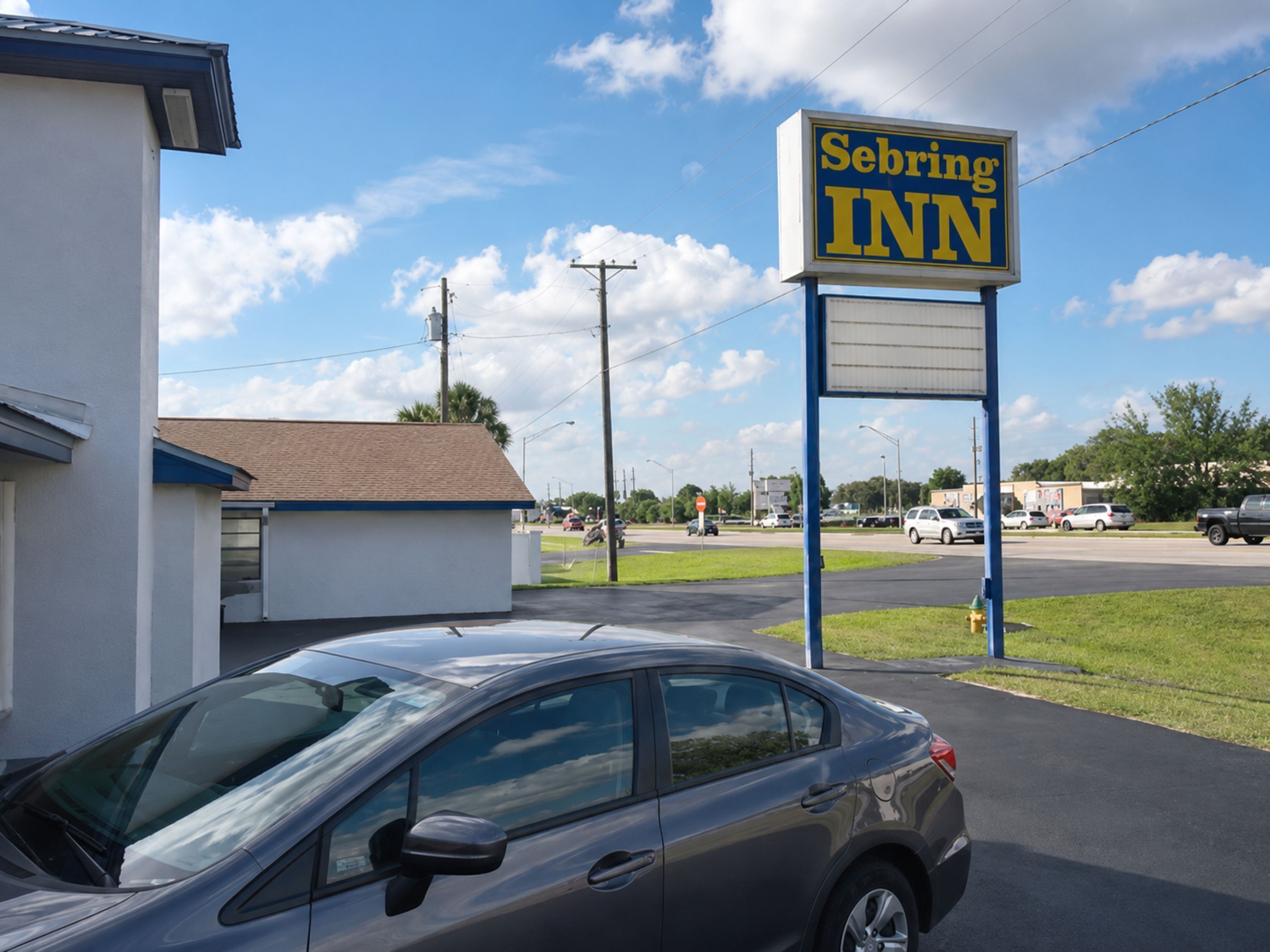 A motel with a sign reading 'Sebring INN' and a parked car in front.