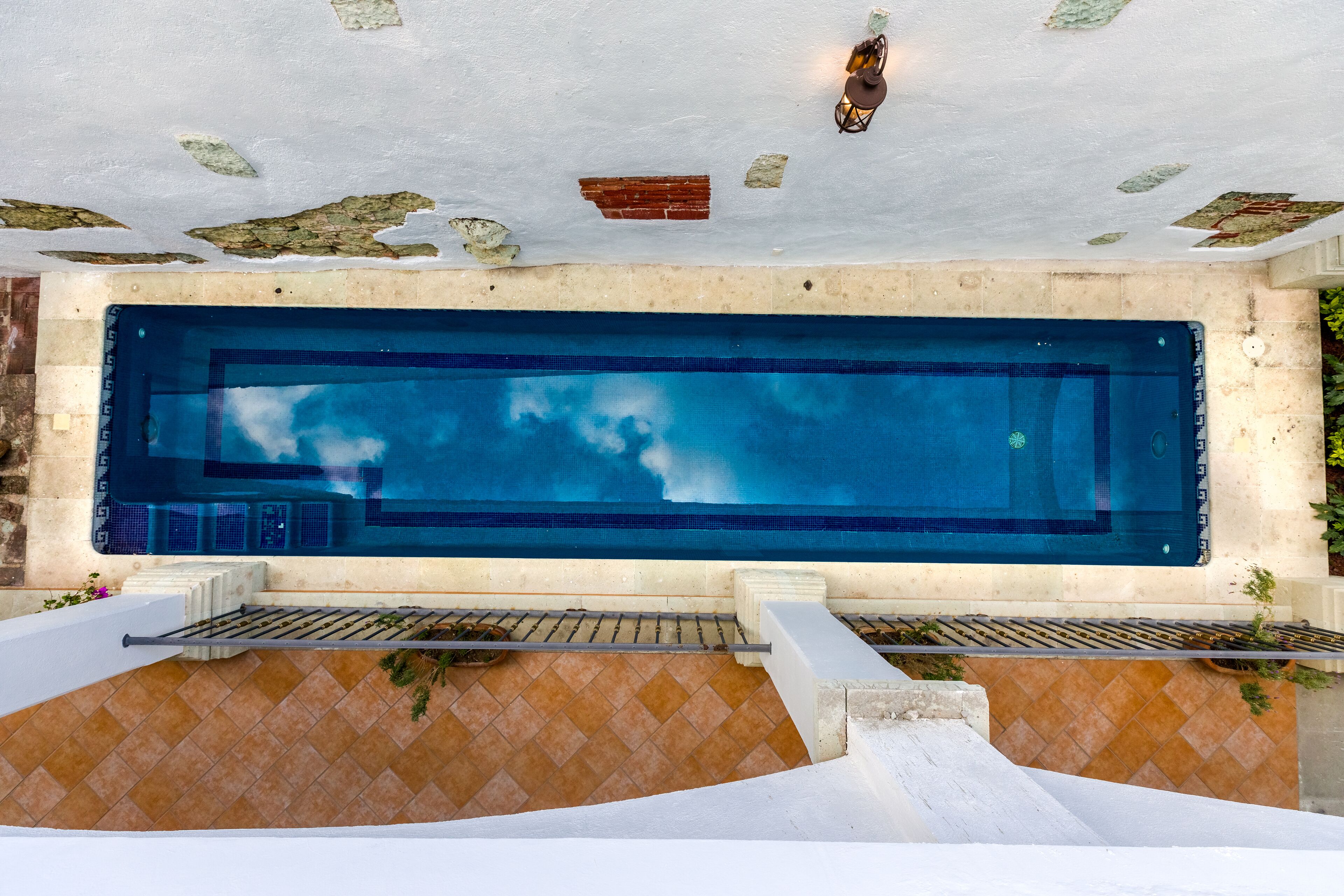 Una piscina rectangular con una zona de terraza empavedada en frente.