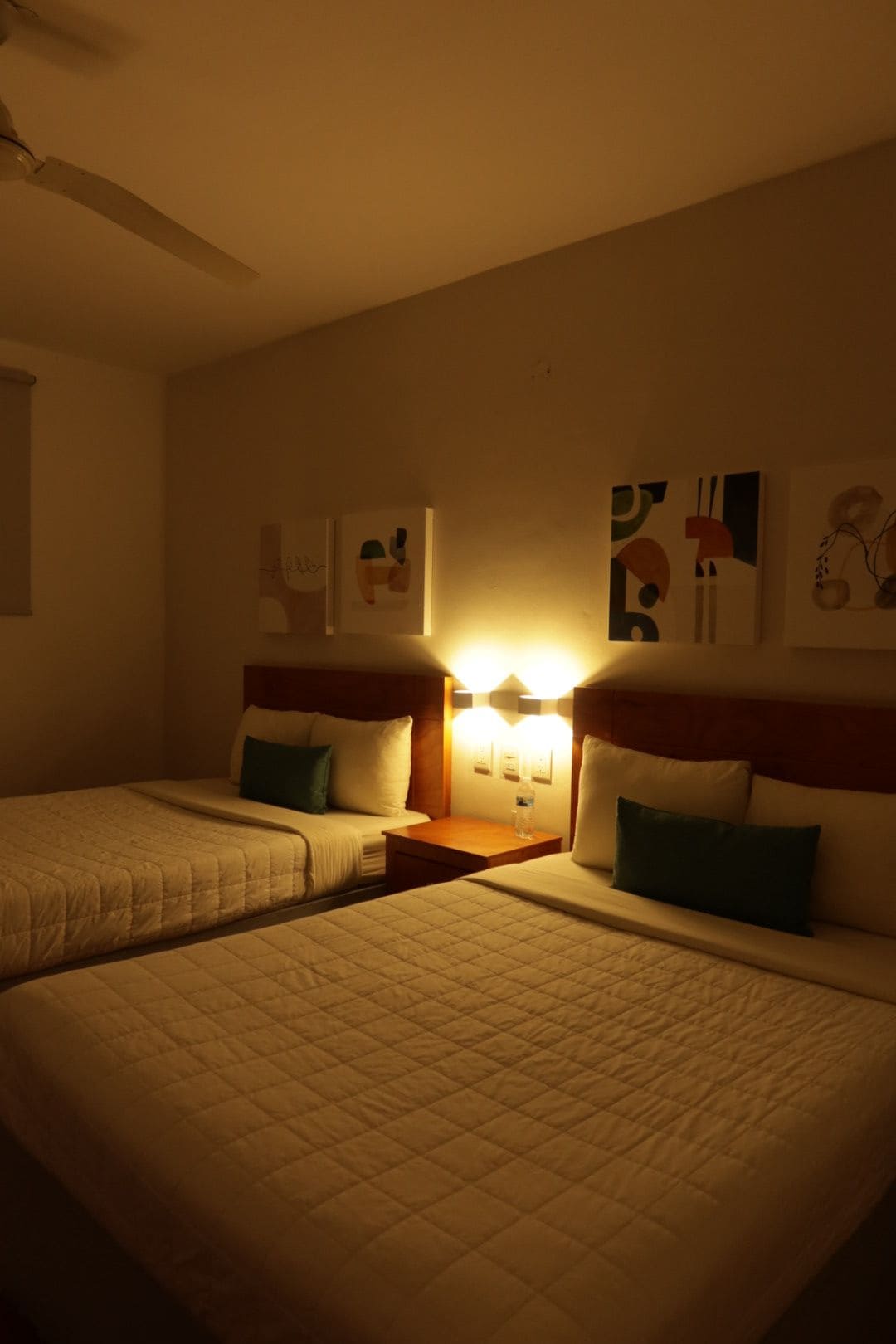 A hotel room with two beds, a nightstand, and wall art.