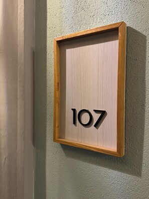 A framed number sign with the number 107 on a textured wall. - Hotel Posada Real (Lagos de Moreno)