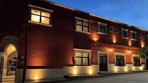 A two-story building with a brick facade, multiple windows, and a well-lit entrance. - Hotel Posada Real (Lagos de Moreno)