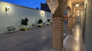 A covered outdoor area with brick pillars, benches, and wall-mounted lights. - Hotel Posada Real (Lagos de Moreno)