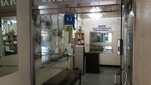 A reception area with a glass door, a reception desk, and a sign indicating room number 9.2. - OxbloodK (Gwangju)