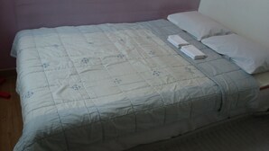 A bed with a quilted bedspread featuring floral patterns, a neatly folded white towel, and two white pillows. - OxbloodK (Gwangju)