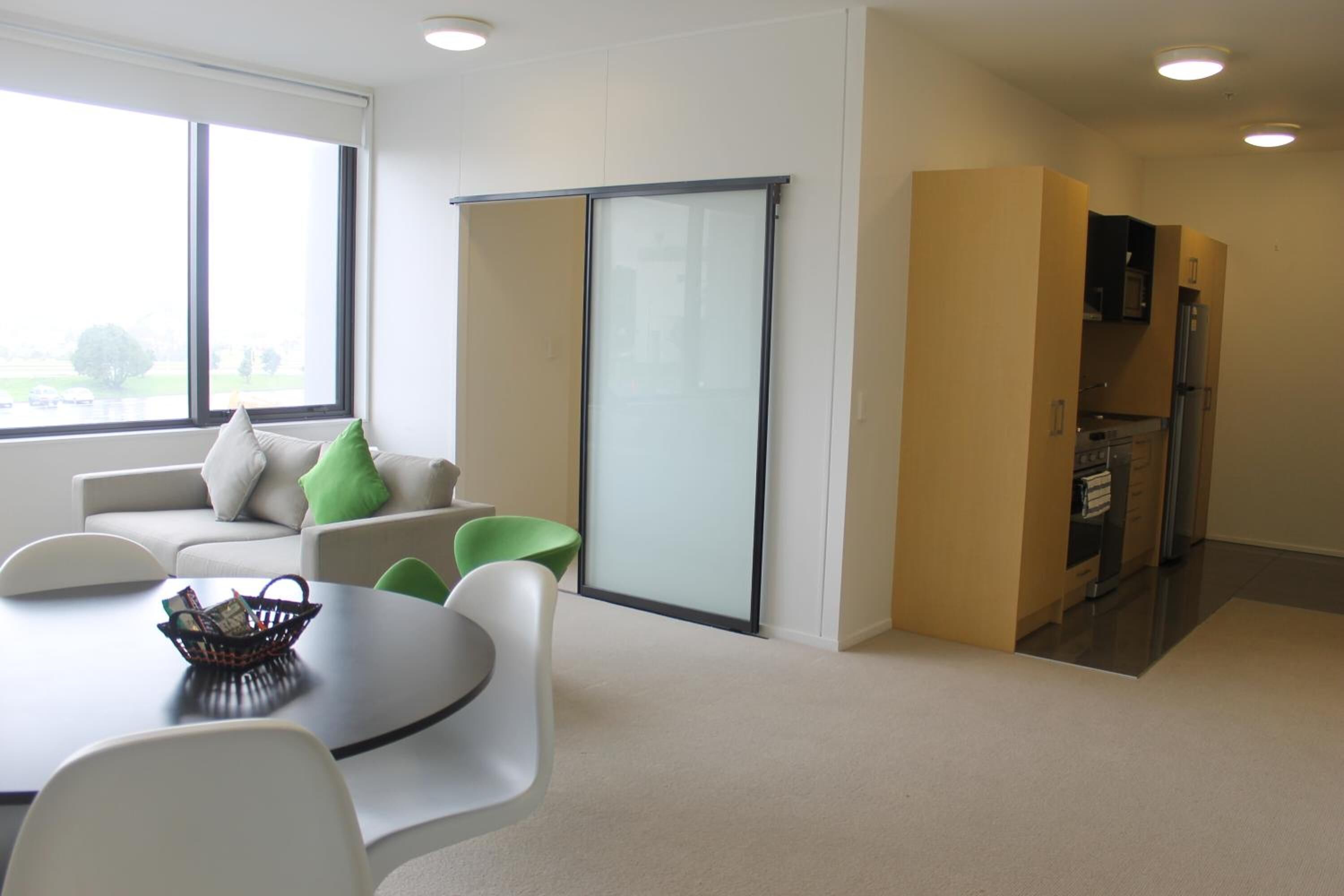 A modern living room with a sofa, chairs, a table, and a sliding glass door.