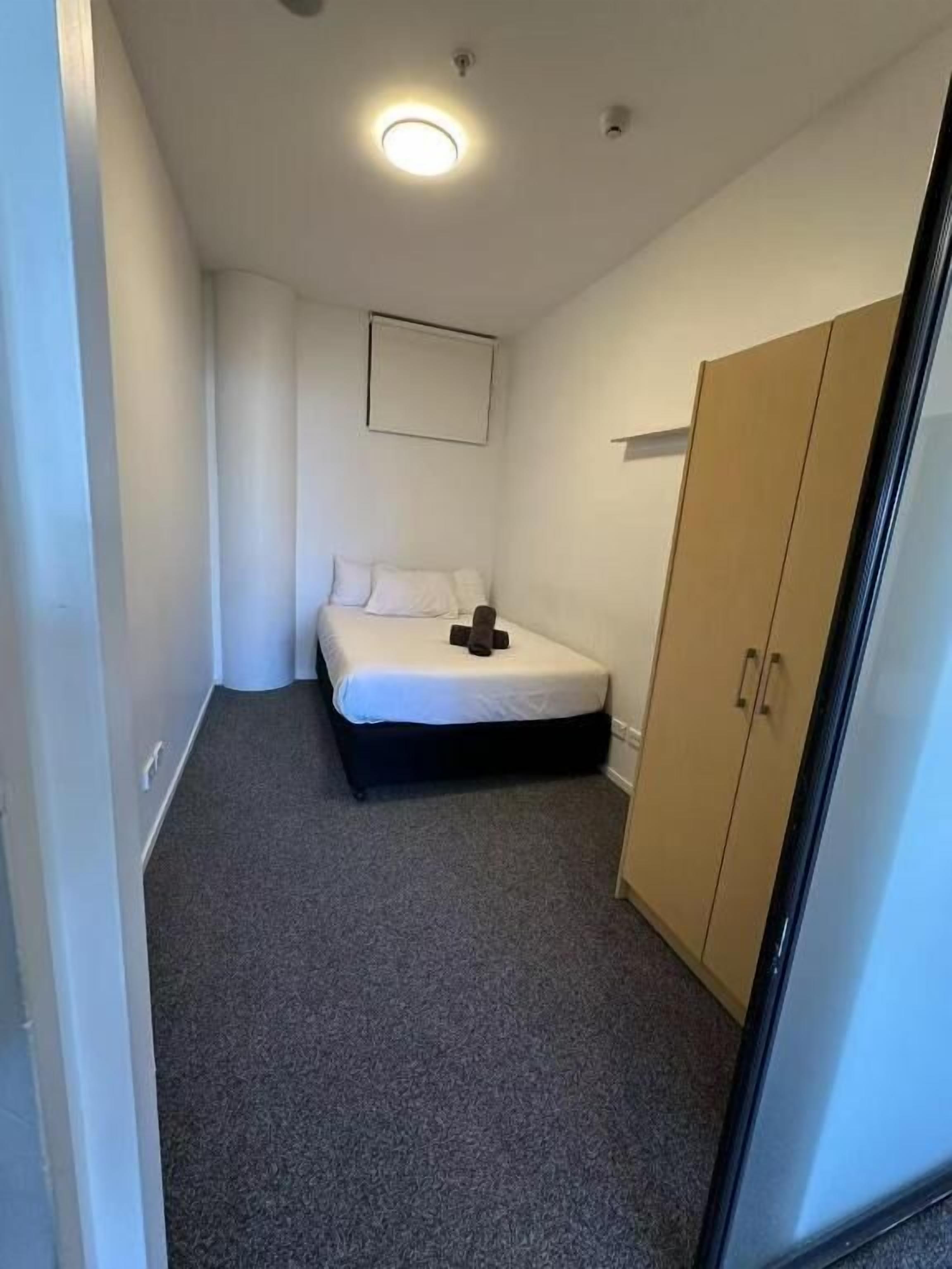 A bedroom with a bed, a wardrobe, and a ceiling light.