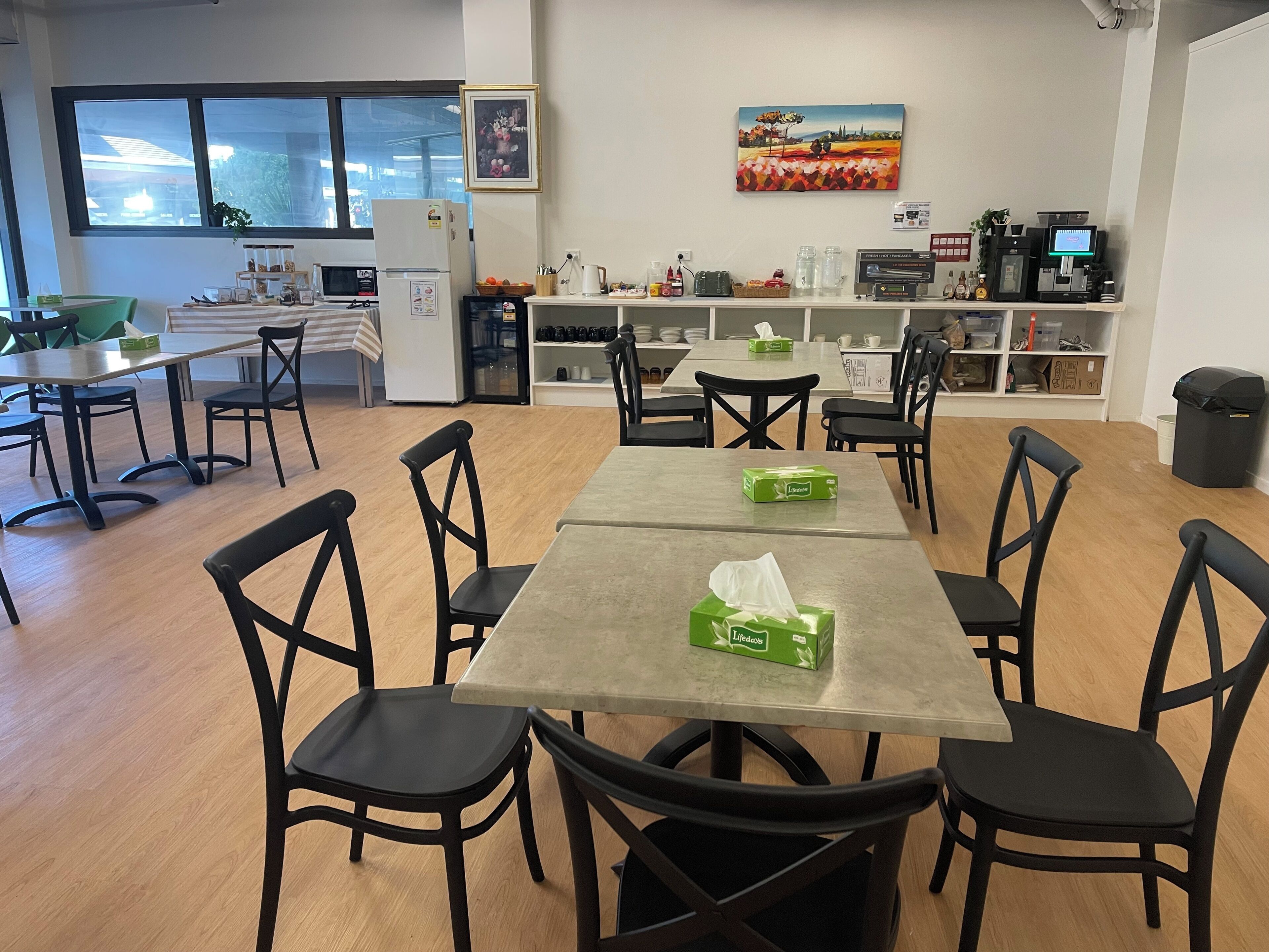Un comedor con una mesa, sillas, refrigerador y ventana.