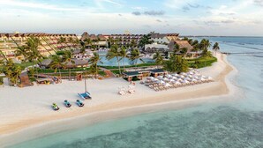A resort with multiple buildings, a pool, and a beach area with umbrellas and lounge chairs. - Ambassador at Grand Velas All Inclusive (Playa del Carmen)