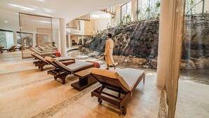 A spa area with sun loungers, a water feature, and a person walking. - Ambassador at Grand Velas All Inclusive (Playa del Carmen)