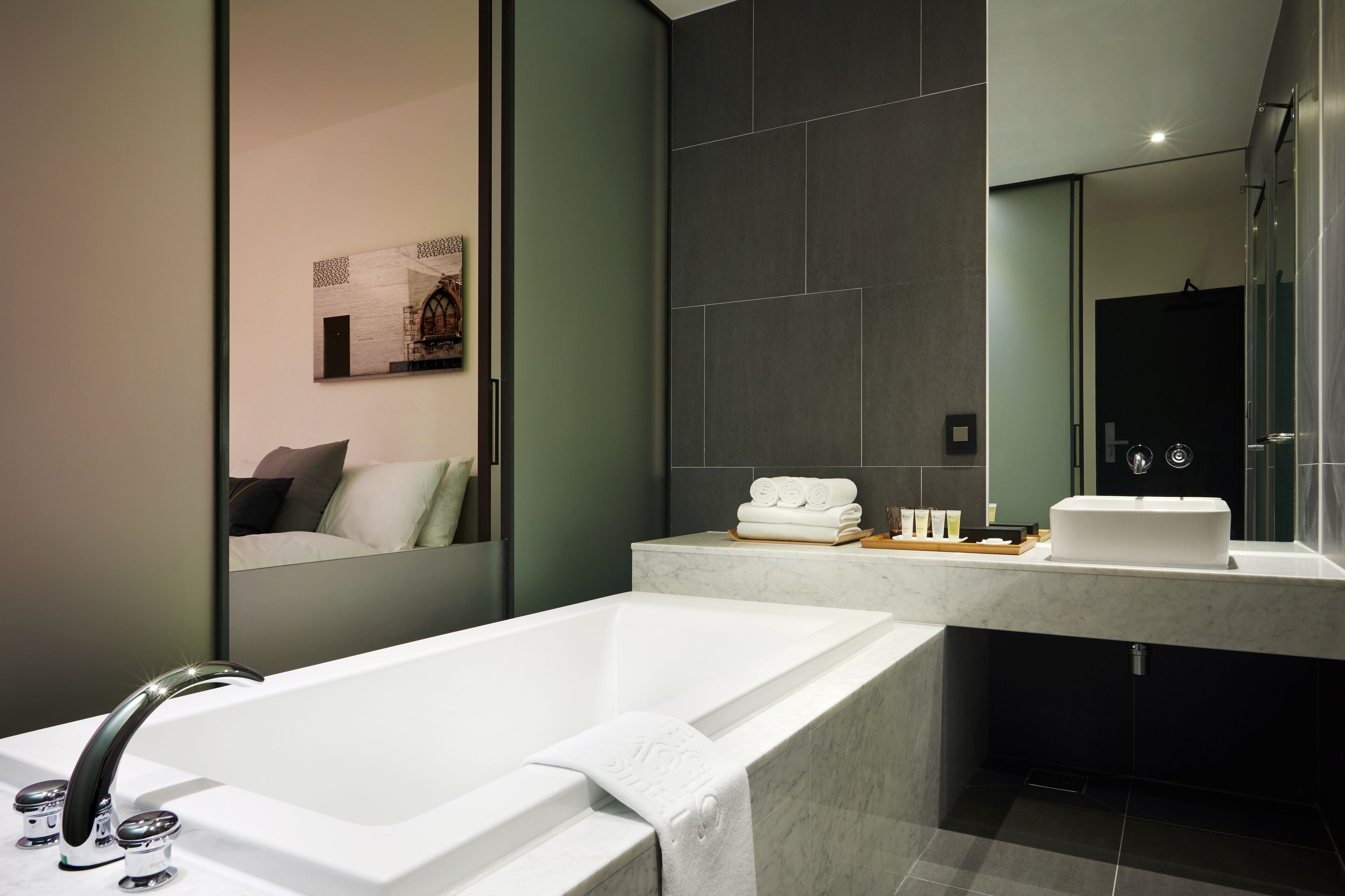 A modern bathroom with a freestanding bathtub, a large mirror, and a vanity with a sink and towel rack.