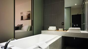 A modern bathroom with a freestanding bathtub, a large mirror, and a vanity with a sink and towel rack.