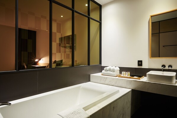 A modern bathroom with a large bathtub, a vanity with a sink, and a large mirror. - The Classic by Hotelone (Wanju)