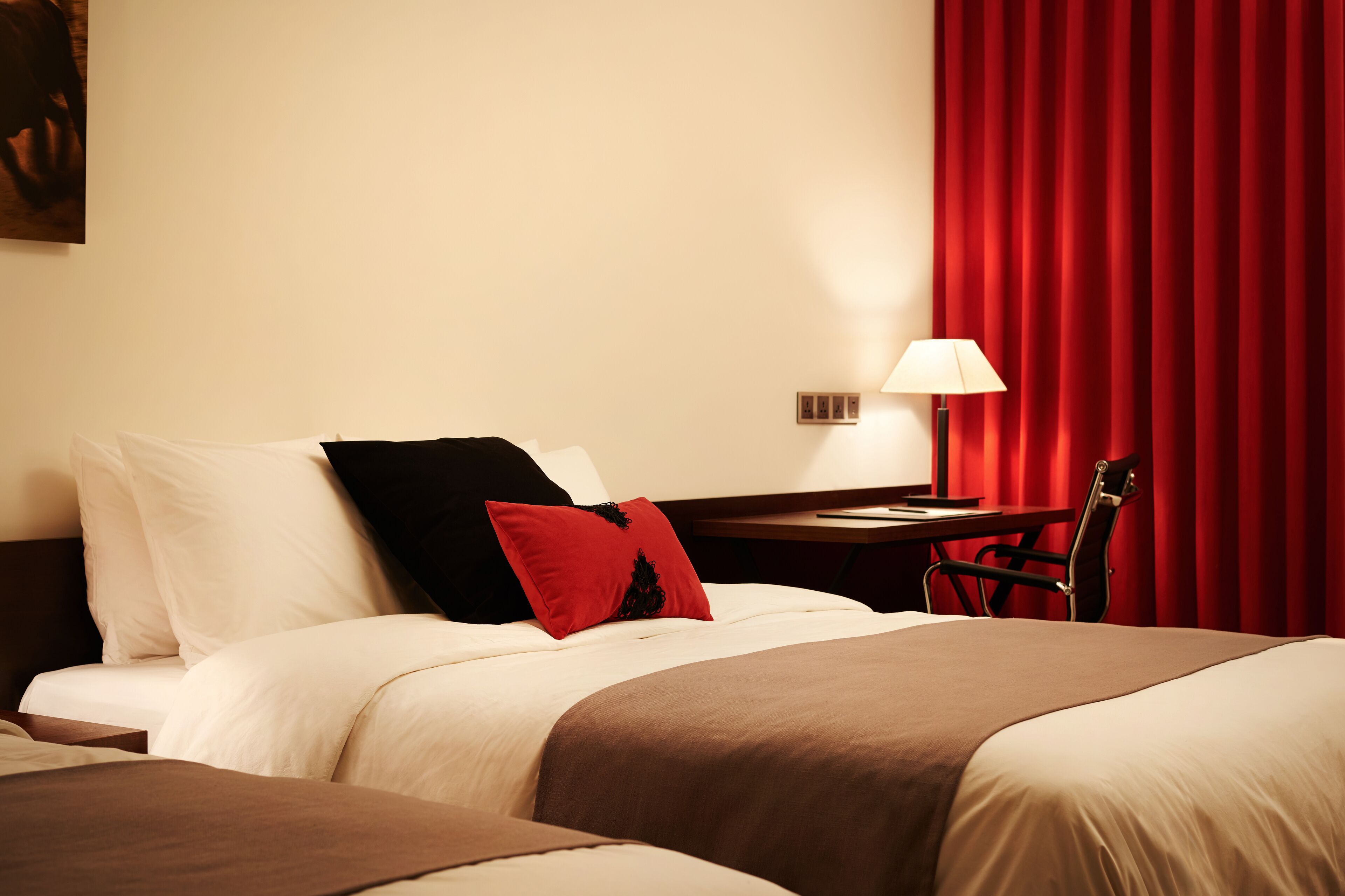 Una habitación de hotel con cama, escritorio, silla y cortina roja.