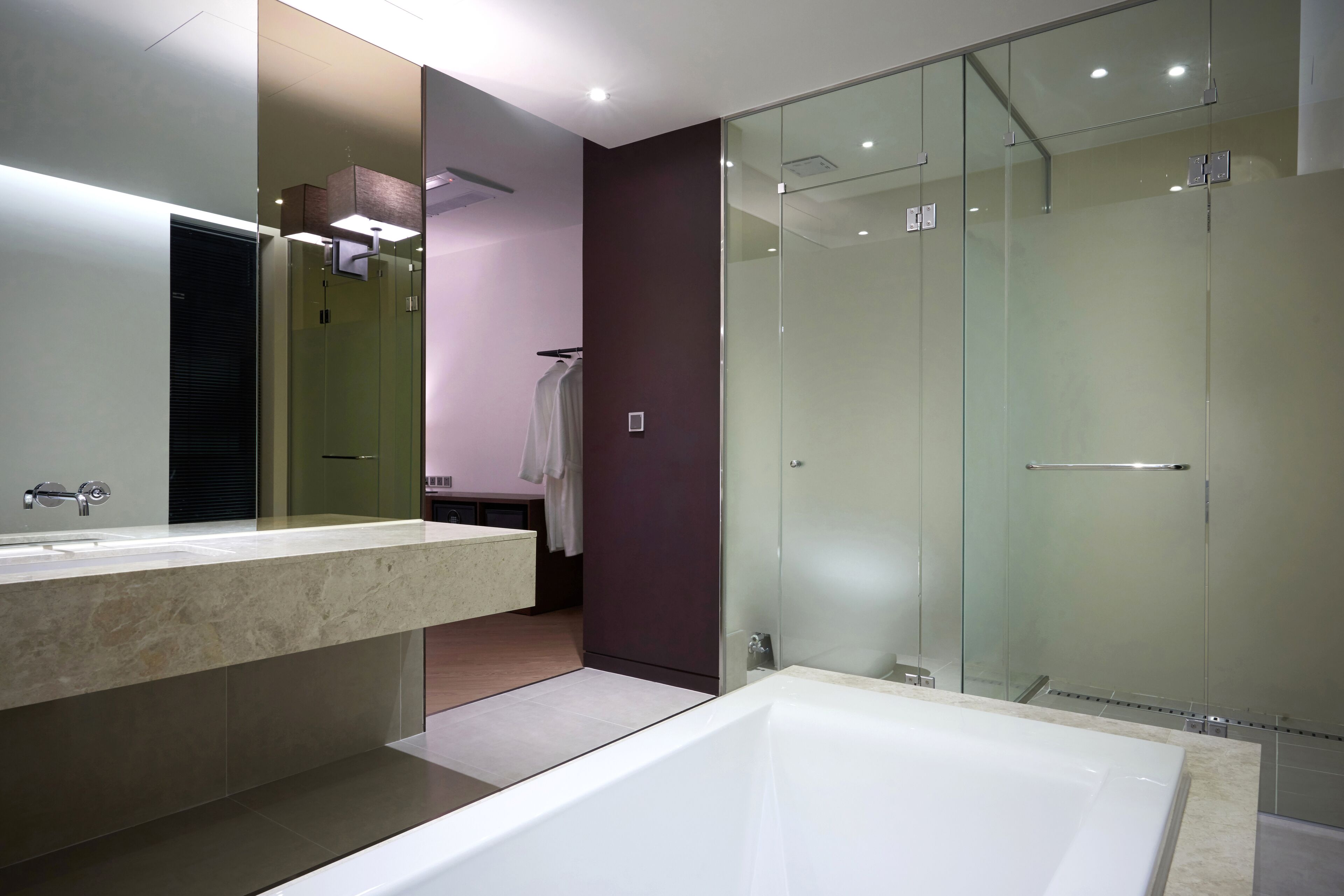 Un baño moderno con un espejo grande, una bañera y un box de ducha de vidrio.