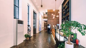 A modern hotel corridor with wooden flooring, a reception desk, and a large potted plant. - The Classic by Hotelone (Wanju)